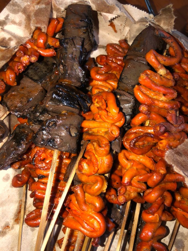 several skewers of food on sticks with meat and sauces all over them