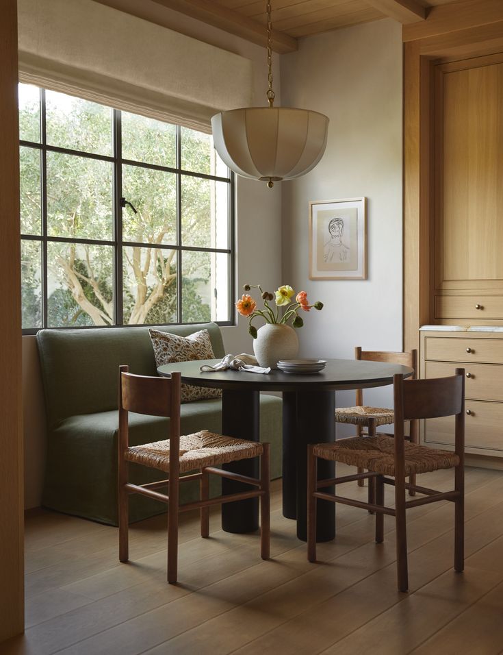 a dining room table with two chairs and a bench in front of a large window