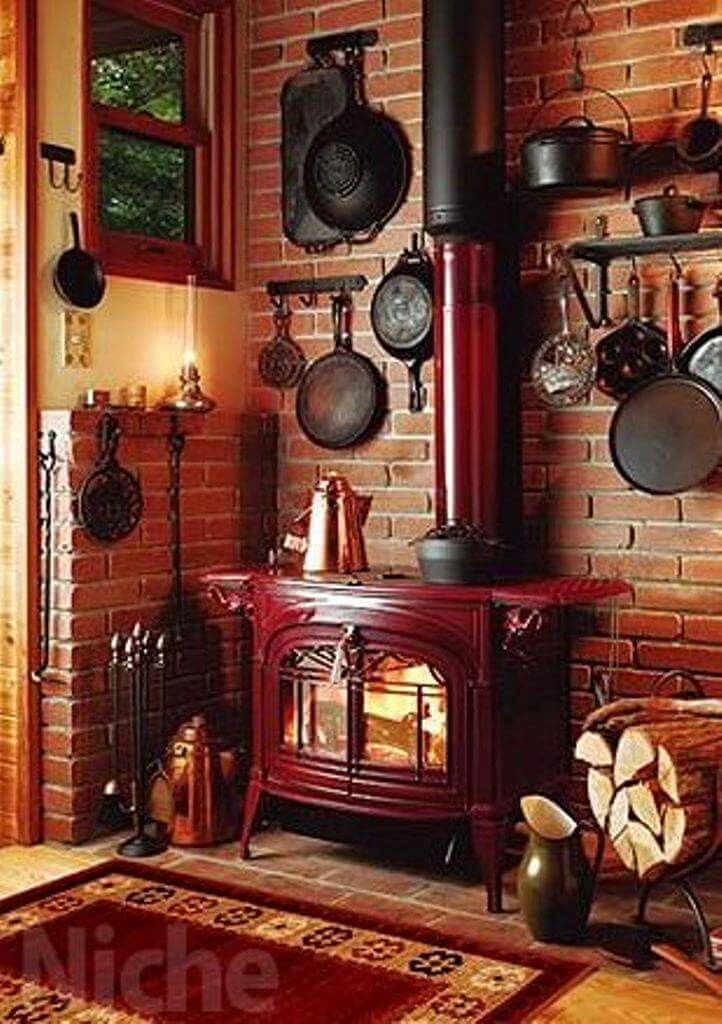 a red stove sitting in the middle of a living room next to a brick wall