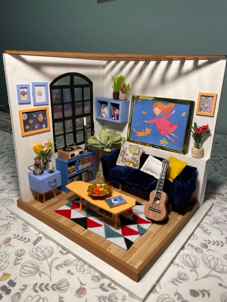 a miniature living room with furniture and pictures on the wall, including a blue couch