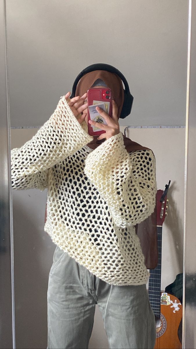 a person taking a selfie in front of a mirror wearing a hat and sweater