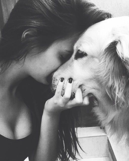 a woman kissing her dog on the nose