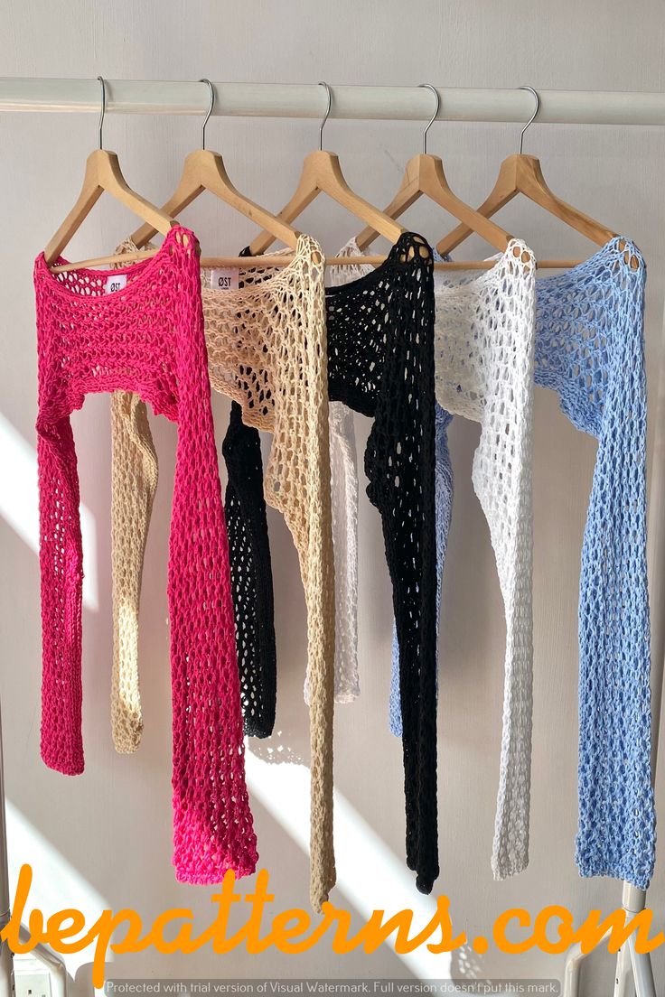 there are four crocheted sweaters hanging on the clothes rack