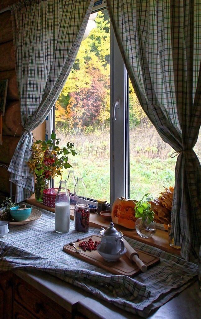 a kitchen with a tea kettle on the counter next to an open window that looks out onto a grassy field