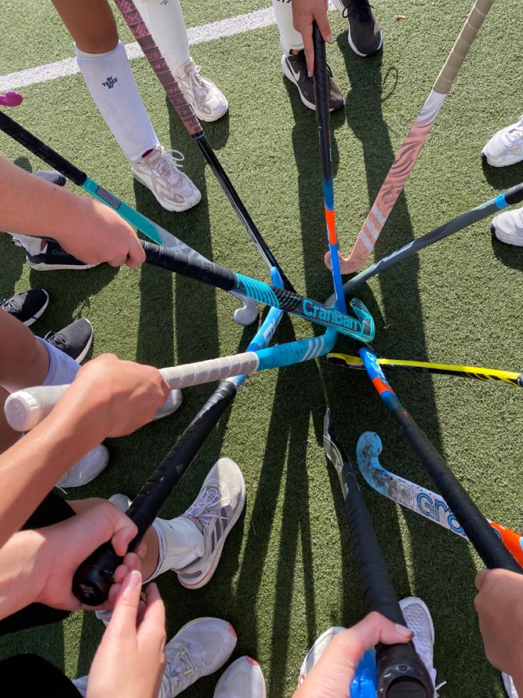 a group of people standing in a circle holding onto baseball bats on top of a field