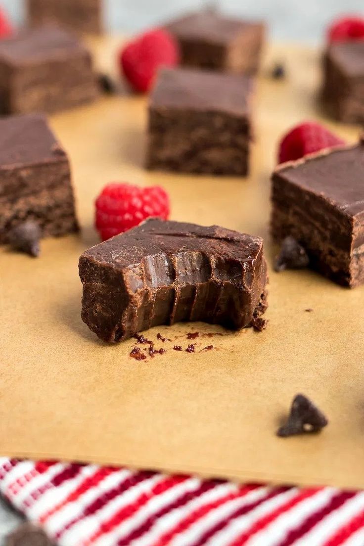 several pieces of chocolate cake sitting on top of a piece of paper next to raspberries