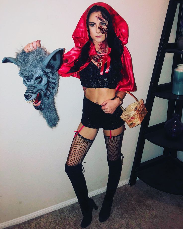 a woman dressed up as a demon holding a purse and a wolf mask on her head