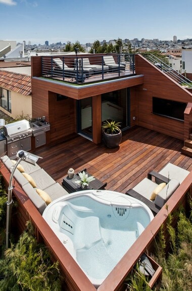 a hot tub sitting on top of a wooden deck next to a building with an open roof