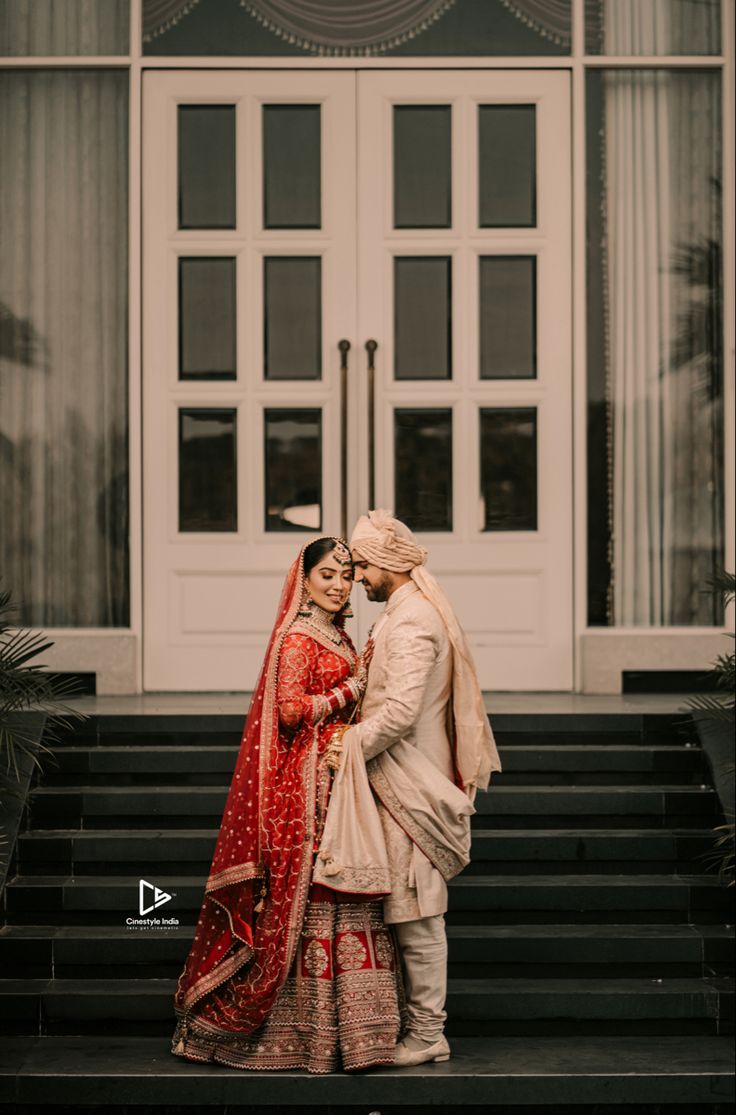 a bride and groom standing on steps in front of a large white building with doors