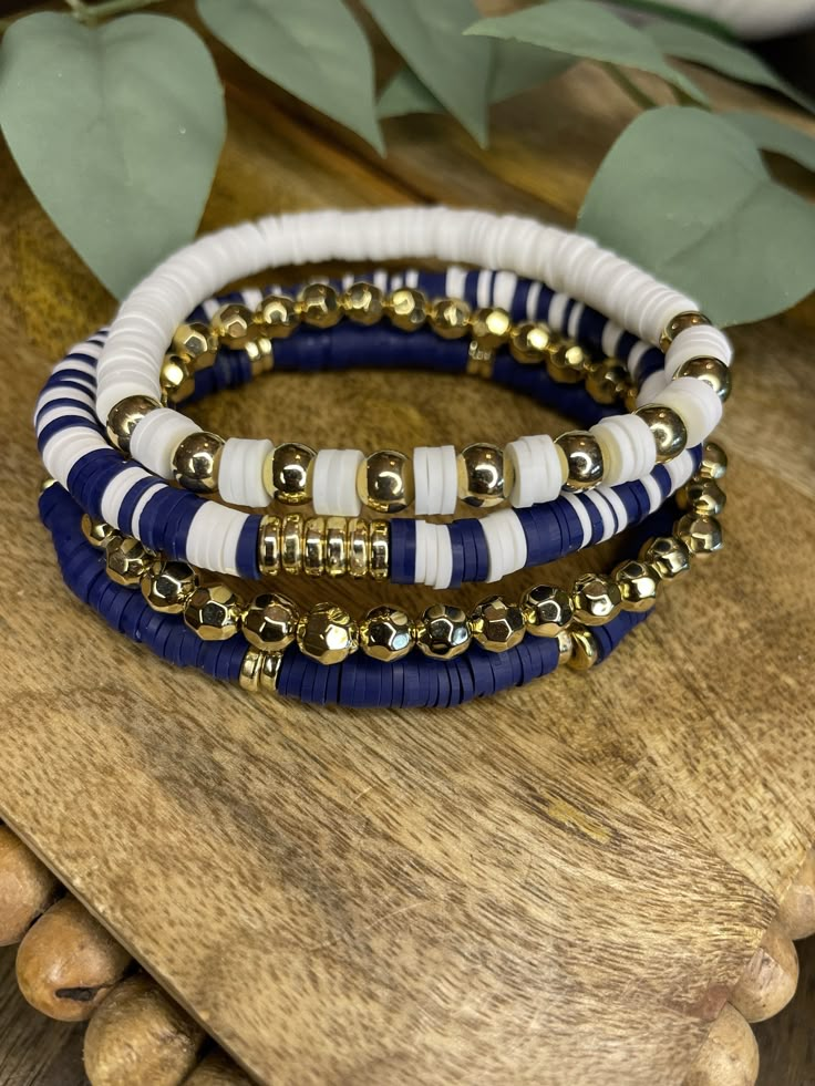 Navy Blue, White and Gold Bracelet Stack Standard size is 7 inches If you'd like bigger or smaller sizes send me message at checkout Care for your bracelets: Do not wear jewelry while bathing, swimming, or exercising. Limit exposure to body oils, perspiration, and cleaning agents. Remove jewelry before going to bed at night. Gold plated metals naturally tarnish over time when exposed to water and body oils Night Jewelry, Cheap Handmade Blue Beaded Bracelets, Cheap Beachy Blue Beaded Bracelets, Blue And Gold Beaded Bracelets, Bead Bracelet Ideas Color Combinations, Dark Bracelet Ideas, Clay Bead Bracelet Stack Ideas, Navy Blue Bracelet, Clay Bead Bracelet Ideas Sports