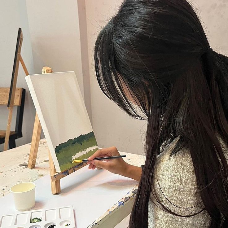 a woman is painting on an easel with paint