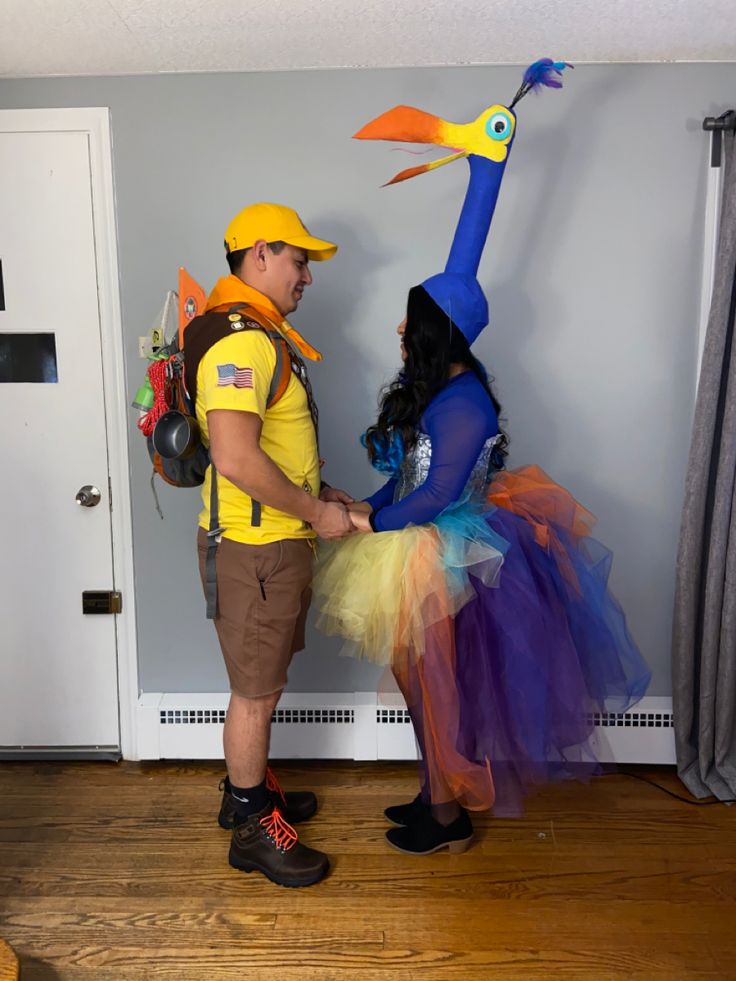 a man and woman dressed up in costumes standing next to each other on the floor