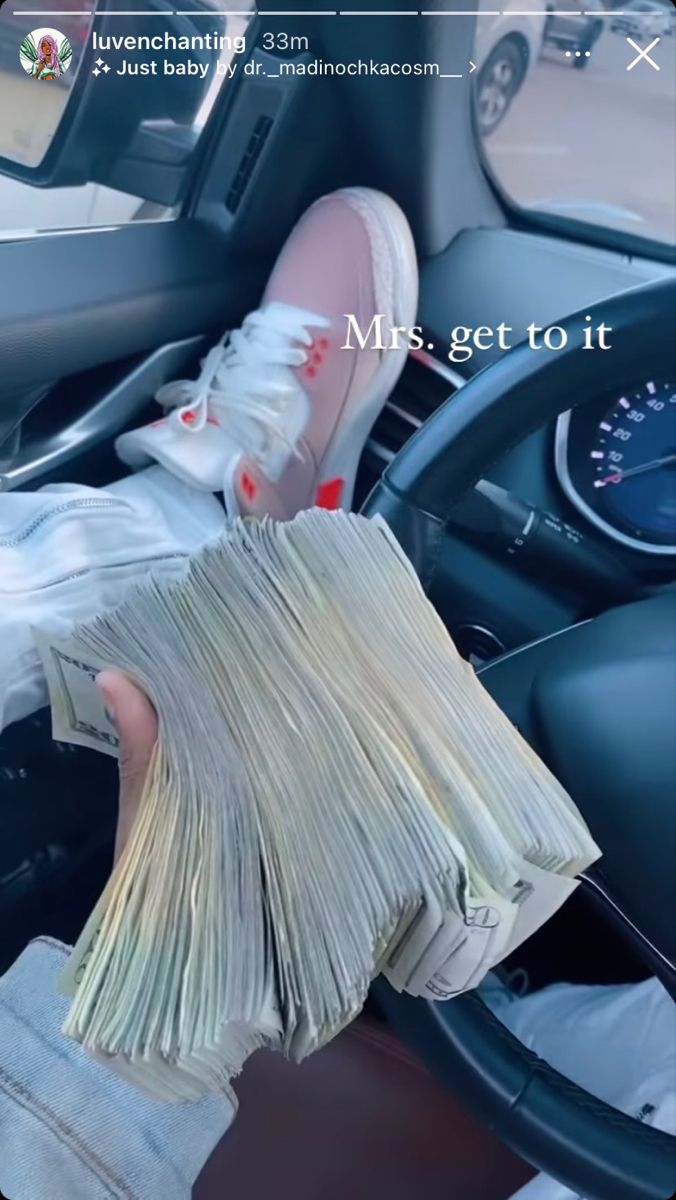 someone is holding money in their hand while sitting in the driver's seat of a car