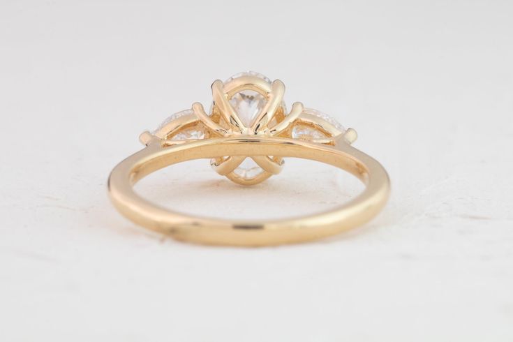 Our sophisticated Audrey ring features an oval center framed by 2 pear accents, expertly crafted to sparkle in all directions. Crafted for maximum brilliance, it's the perfect ring for a modern romantic. Shown with a ~8.5x6mm (~1.2ct) lab diamond in a 18K yellow gold setting, 1.6mm band, model ring size - 4.5 Show with a 2ct Marquise lab diamond crafted in 18K yellow gold, 1.8mm band Elegant 14k Gold Three Stone Cluster Ring, Modern Pear-shaped Wedding Rings, Elegant Trillion Cut 14k Gold Wedding Jewelry, Classic Pear-shaped Cluster Ring For Wedding, 14k Gold Pear-shaped Cluster Ring With Prong Setting, Wedding Cluster Ring With Three Stones In 14k Gold, Pear-shaped 14k Gold Cluster Ring With Prong Setting, Elegant Pear-shaped Cluster Ring With Prong Setting, Yellow Gold Three Stone Pear-shaped Ring