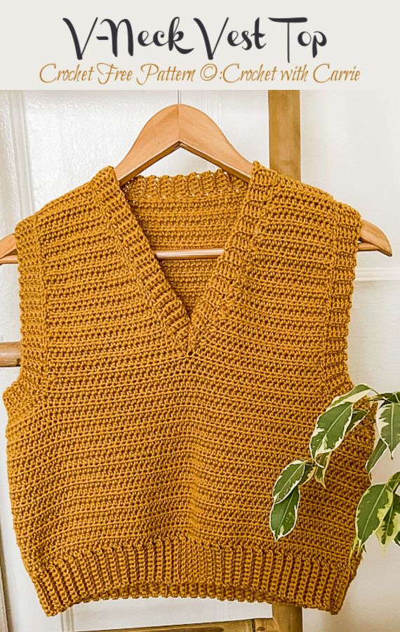 an orange knitted sweater hanging on a wooden hanger next to a potted plant