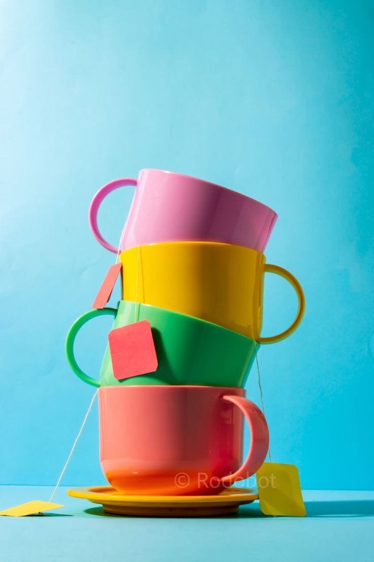 colorful cups stacked on top of each other with sticky notes attached to them, against a blue background