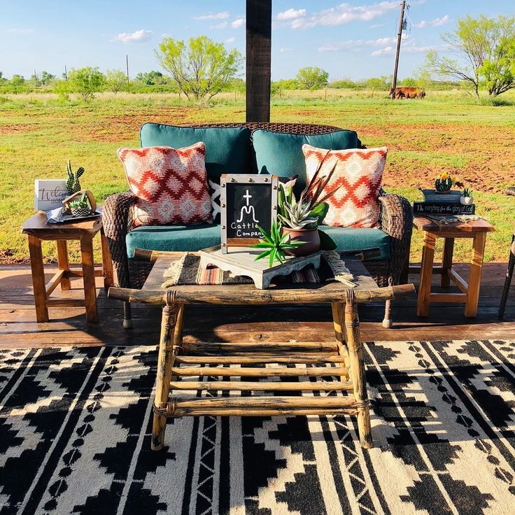 an outdoor living area with couches, tables and rugs on the ground outside