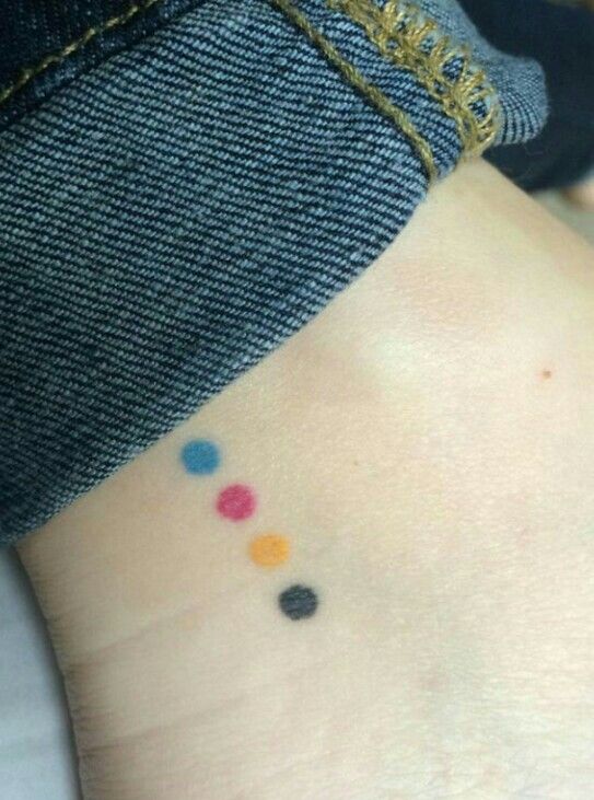 a person with a small tattoo on their ankle that has multicolored dots on it