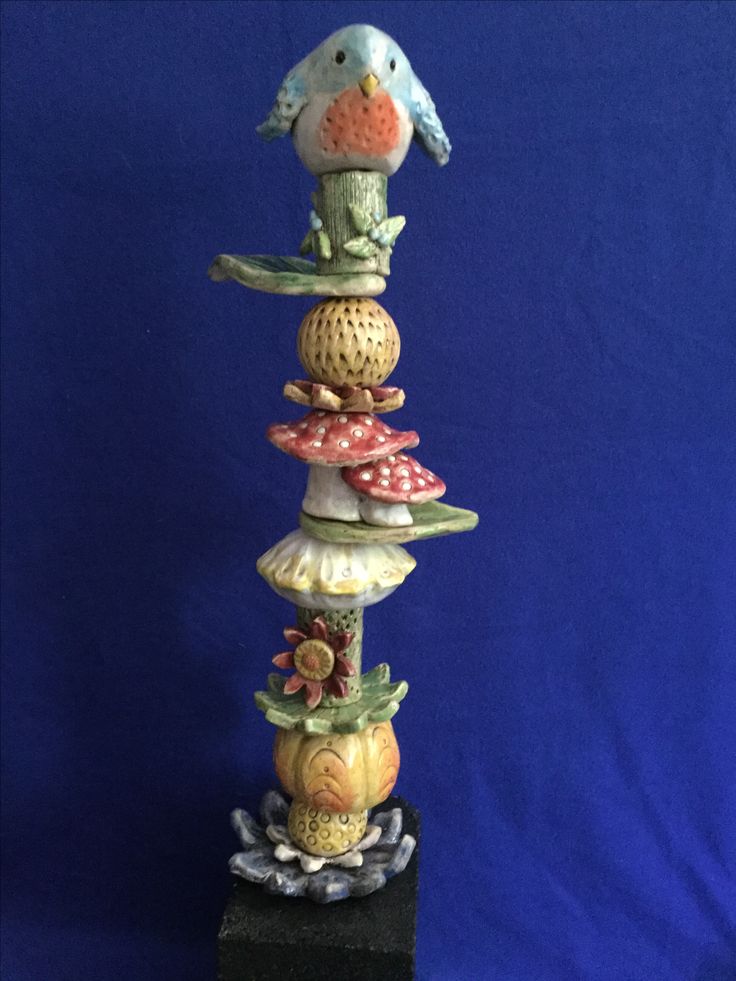 a tall stack of ceramic figurines sitting on top of a black stand against a blue background