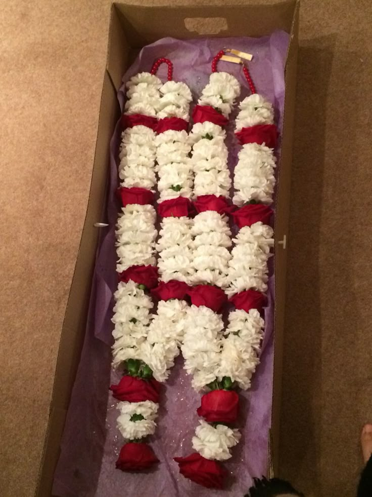 an open box filled with white and red flowers sitting on top of a carpeted floor