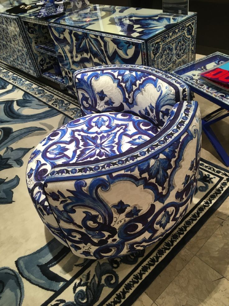 a blue and white chair sitting on top of a tile floor next to a mirror