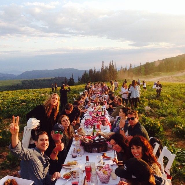 a group of people sitting at a long table with food