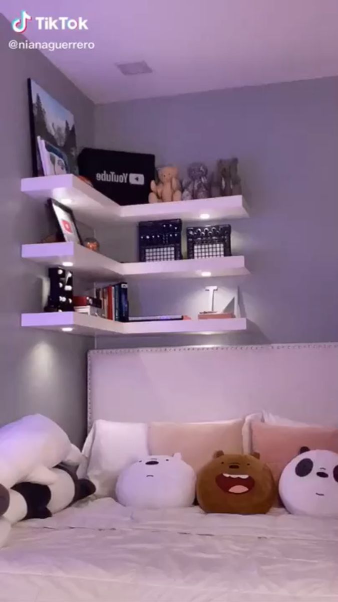 there are stuffed animals on the bed in this small room with bookshelves and shelving