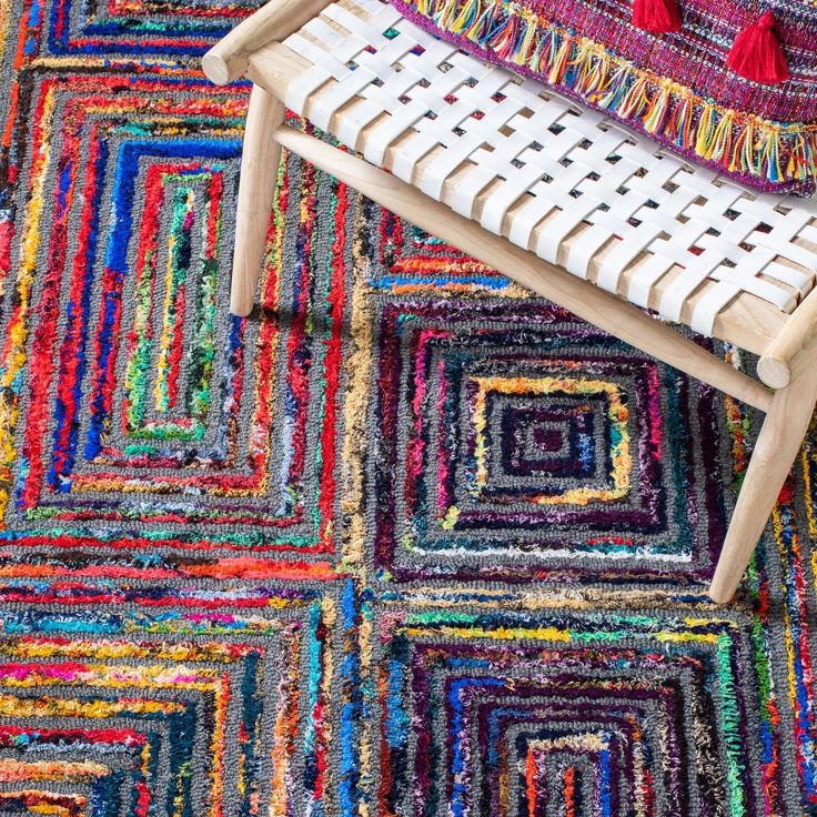 a colorful rug with different colored squares and fringes on the floor next to a chair