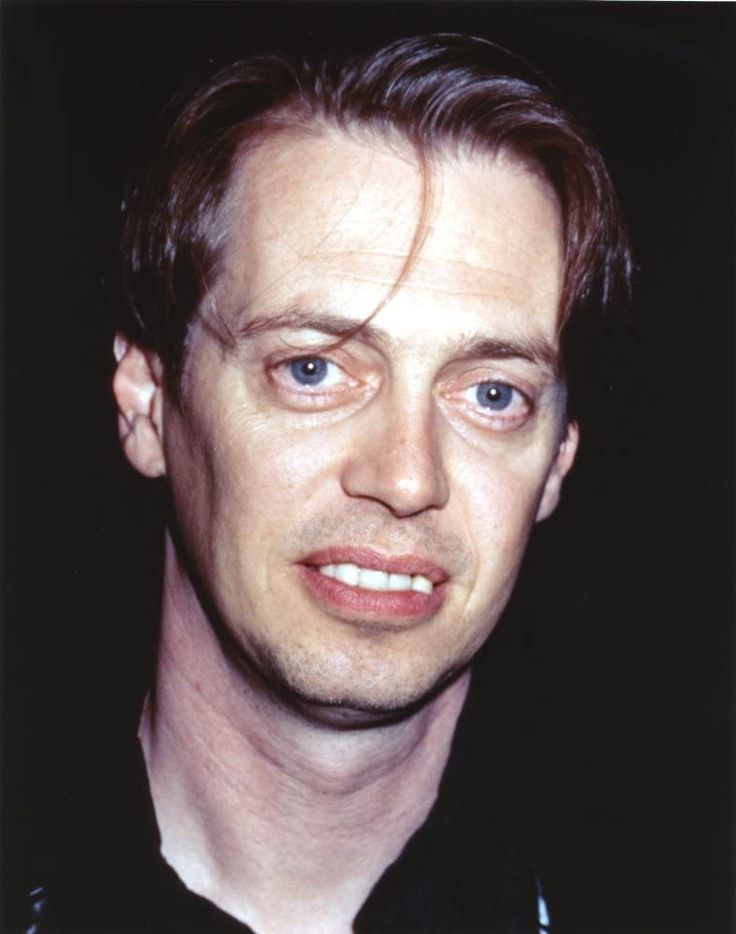 a close up of a person wearing a black shirt and tie with his eyes wide open