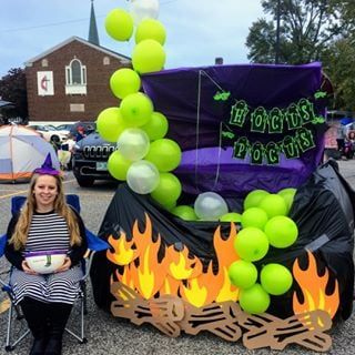 a woman sitting in front of a campfire with green balloons on top of it