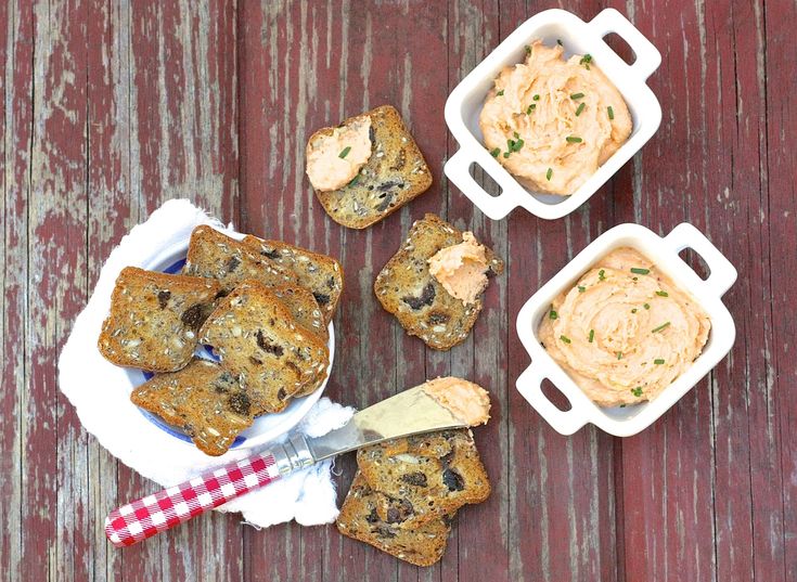 some food is sitting in small containers on a wooden table next to a knife and fork