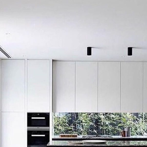 a modern kitchen with white cabinets and black counter tops, along with an island in the middle