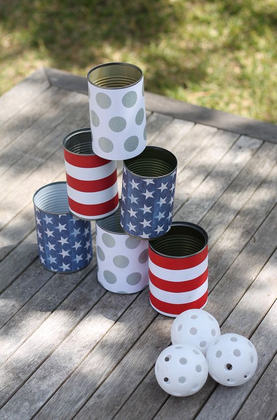 four tin cans with stars and stripes painted on them sitting on a wooden table outside