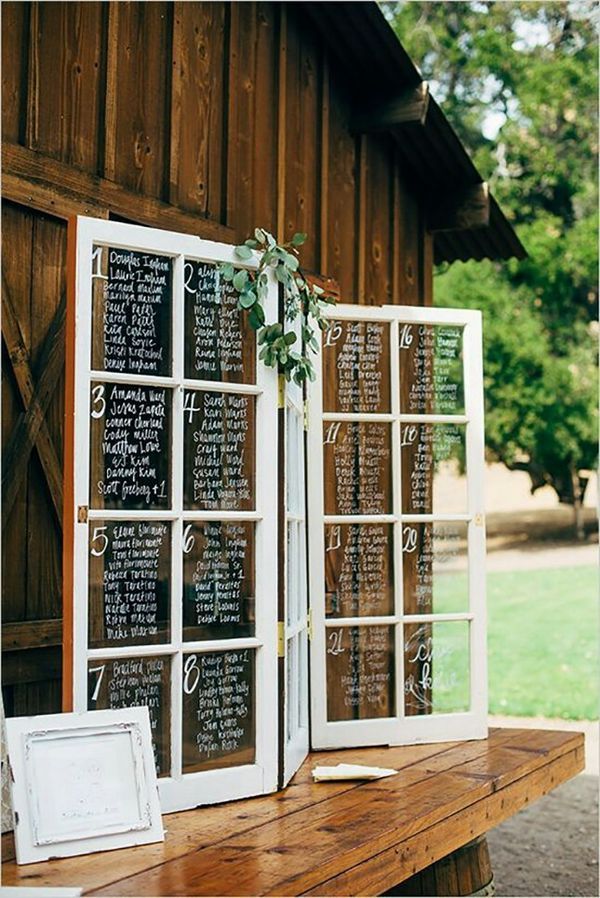 an old window is decorated with greenery and chalkboard for the wedding guests to write their names on