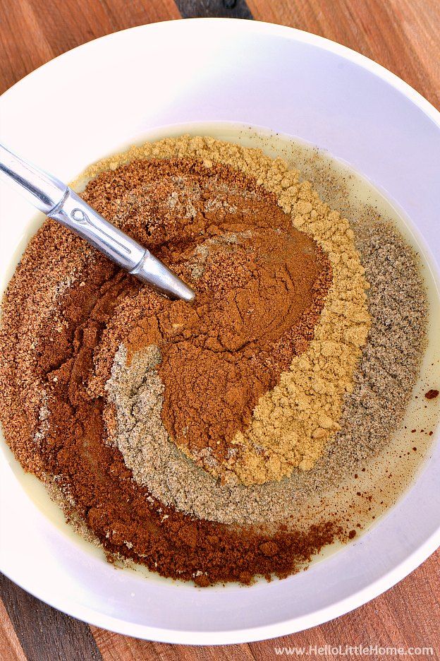 a white bowl filled with spices on top of a wooden table