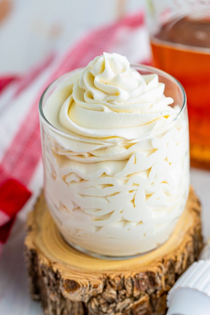 a glass jar filled with whipped cream sitting on top of a tree stump next to honey