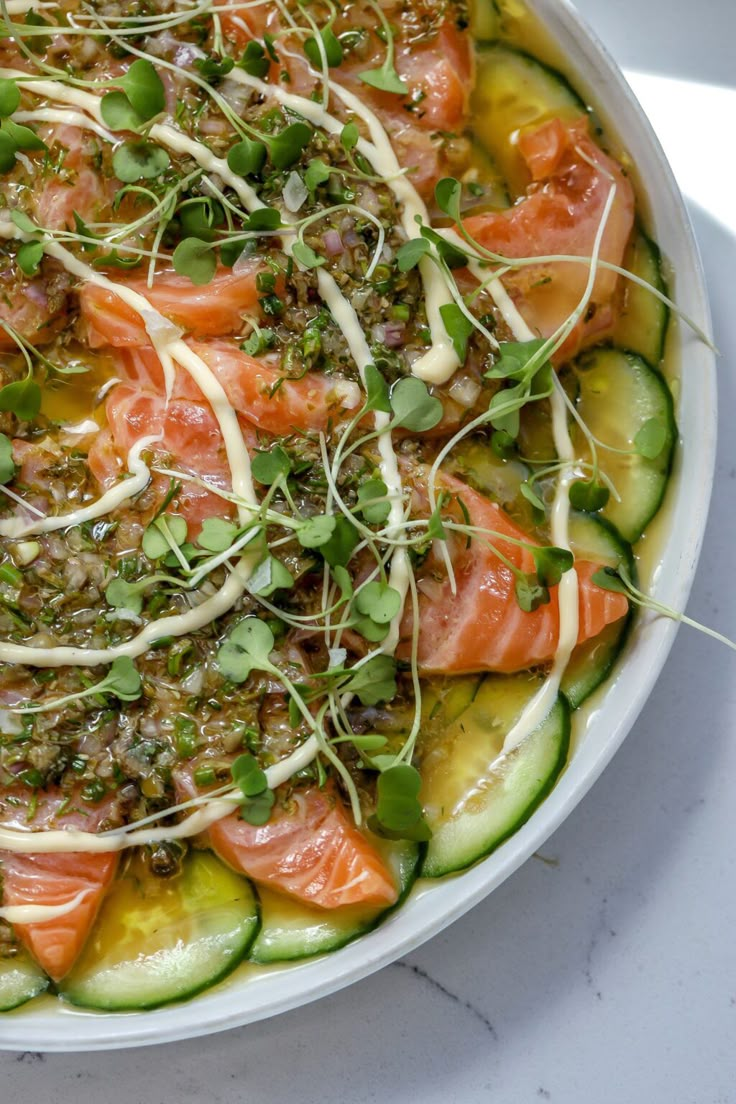 a white bowl filled with sliced up salmon and cucumbers