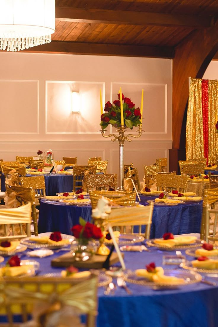 the tables are set up with blue linens and gold chairs for an elegant event