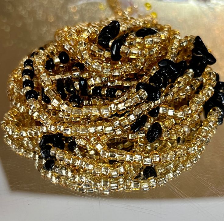 **Please allow up to 5-7 business days for processing time for Waistbeads, Free US Shipping for orders over $75 ** Our stunning Black Love Waistbeads, are perfect for adding a touch of elegance and tradition to your style. These waistbeads feature a beautiful Black and Gold throughout the waistbead. Crafted with high-quality 8/0 and 6/0 glass beads, they offer both durability and beauty. Designed to fit most with a standard length of 60", these traditional tie-on waistbeads allow you to customiz Polished Beaded Bracelets For Party, Party Beaded Bracelets With Polished Beads, Elegant Gold Beads With Black Details, Party Polished Round Beaded Bracelets, Elegant Waist Beads With Spacer Beads As Gift, Elegant Waist Beads With Spacer Beads For Gift, Elegant Faceted Waist Beads As Gift, Festive Gold Beaded Necklaces With Black Beads, Elegant Waist Beads As A Gift