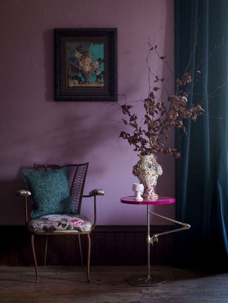 a vase with flowers on a table next to a chair