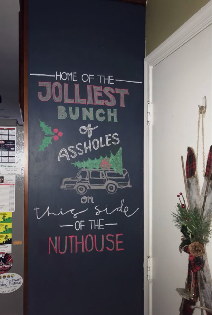 a chalk board with writing on it in a kitchen next to a christmas tree and other decorations