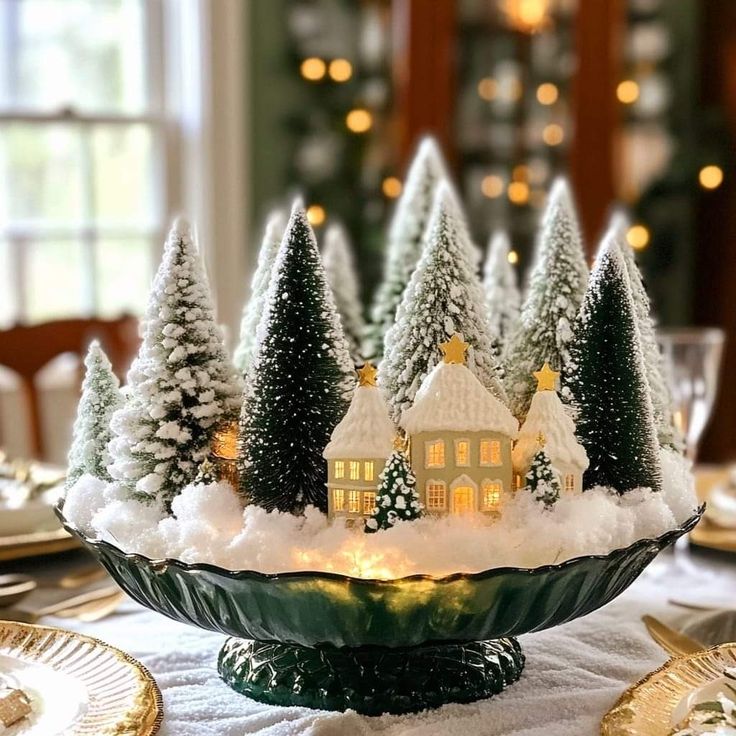 a christmas centerpiece with trees and lights in the shape of houses on a platter