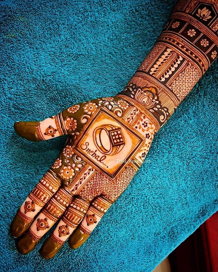 a hand that is decorated with henna and designs on the palm, sitting on a blue towel