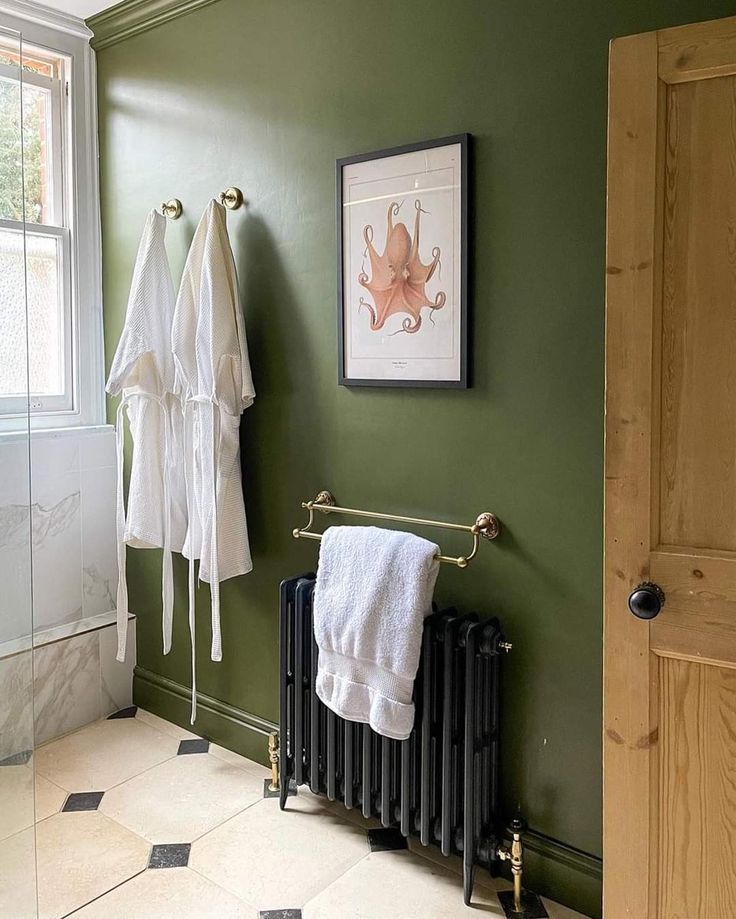 a bathroom with green walls and white towels hanging on the radiator next to an open door