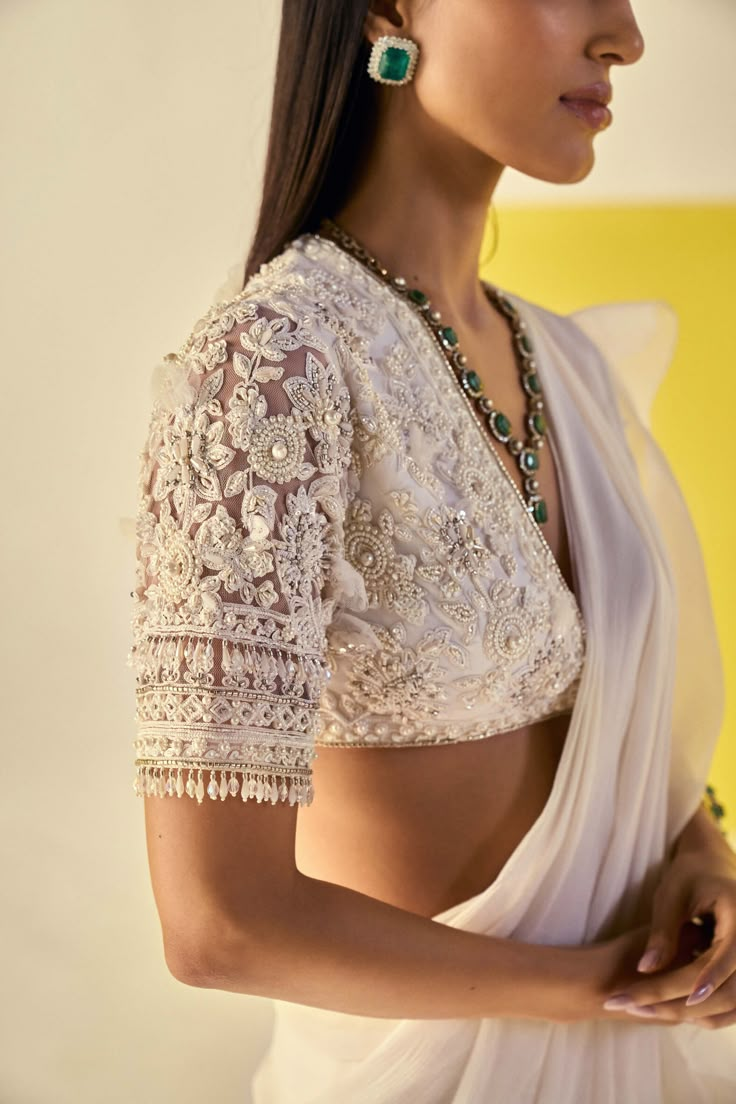 Editor's Note Embrace elegance and grace in this ivory net pearl embroidered elbow sleeves blouse and chiffon organza draped ruffled sari. The intricate pearl embroidery adds a touch of sophistication, while the cascading ruffles of the sari create a captivating look. Fabric: Blouse: net, sari: chiffon/organza Color: Ivory Components: Sari and blouse Occasion: Festive and Wedding Guest Note: Product colour may slightly vary due to photographic lighting sources Care: Dry clean only About the Desi Pearl Saree, Ivory Saree, Net Sari, Pearl Blouse, Ridhi Mehra, Saree Blouse Styles, Saree Chiffon, Net Blouse, Net Blouses