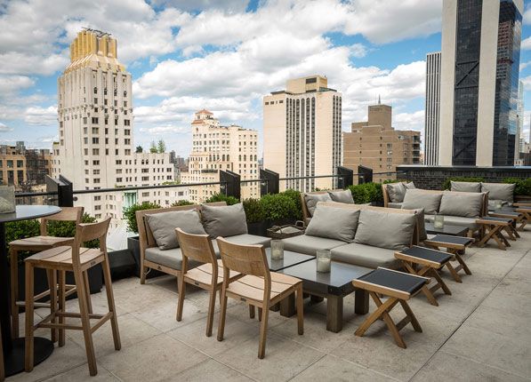 an outdoor seating area on the roof of a building with city skyline in the background