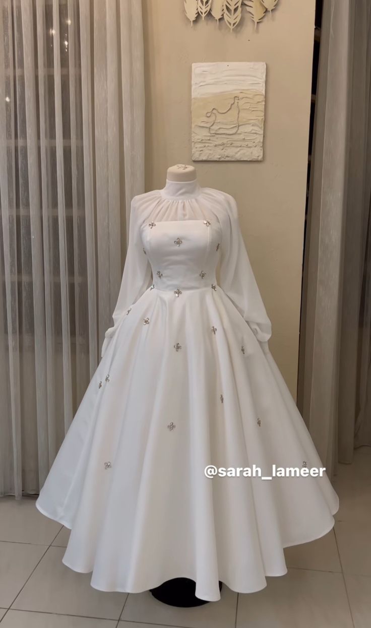 a white dress on display in front of curtains