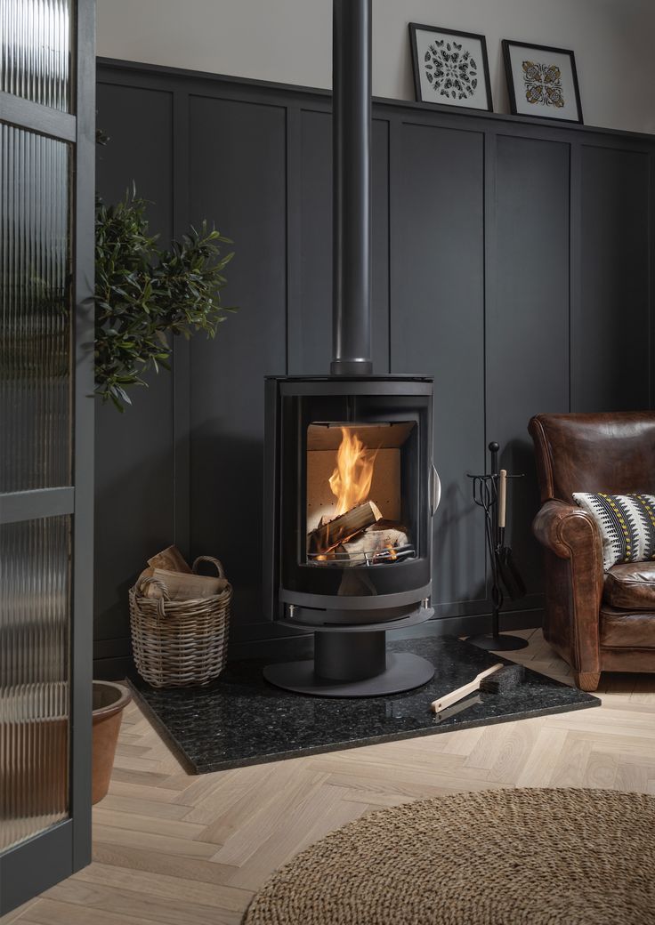 a wood burning stove sitting inside of a living room next to a brown leather chair