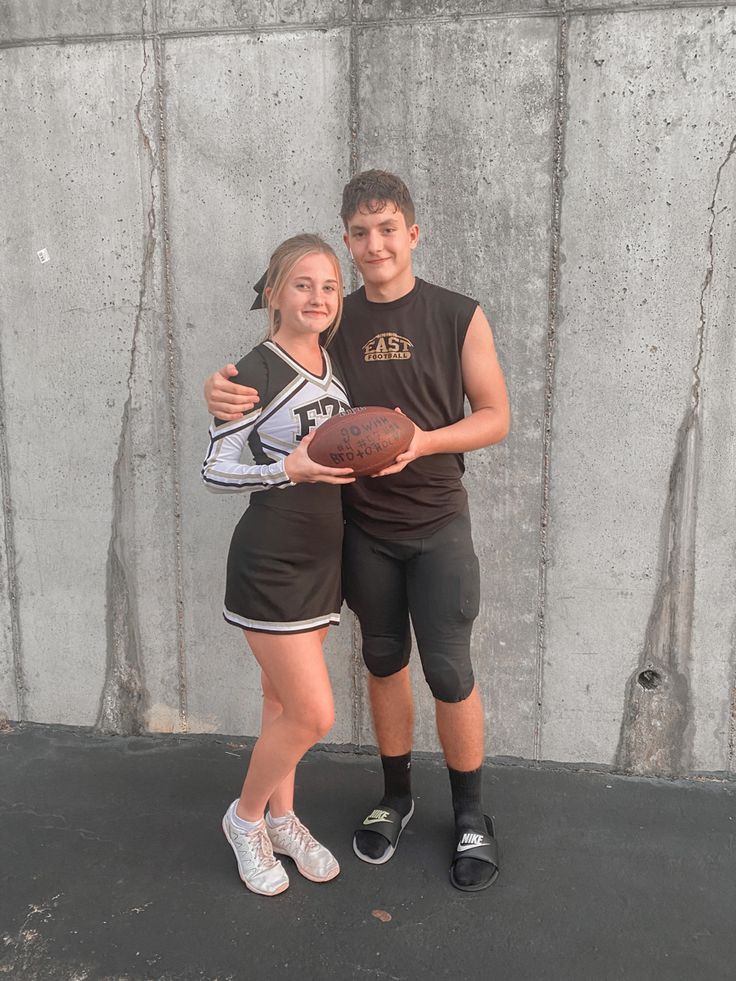 two people standing next to each other holding a football