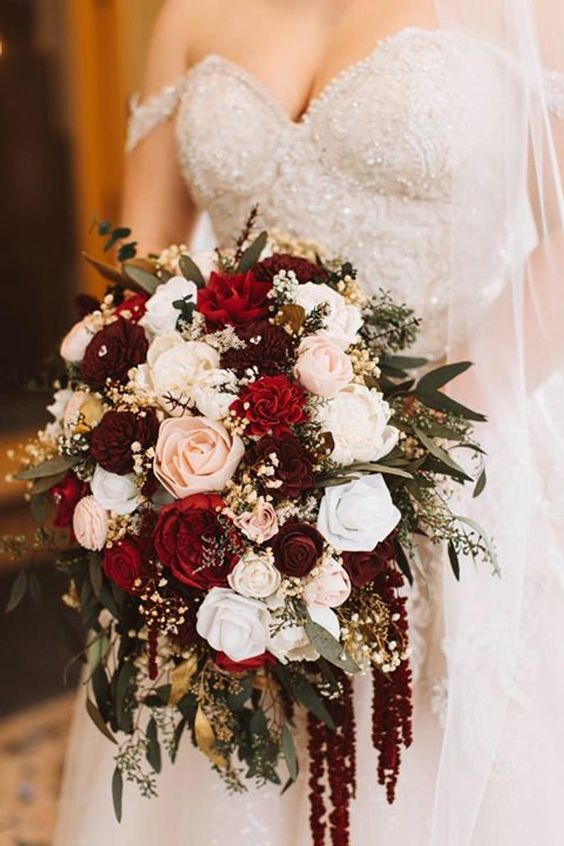 a bridal holding a bouquet of red and white flowers